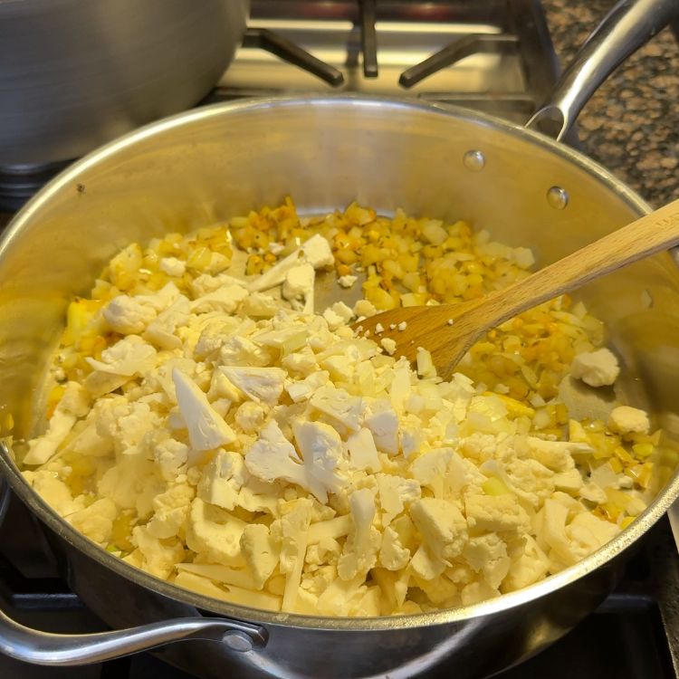 Fresh cauliflower florets added to the pan with onions and tempered spices for Cauliflower Vepudu Fry.