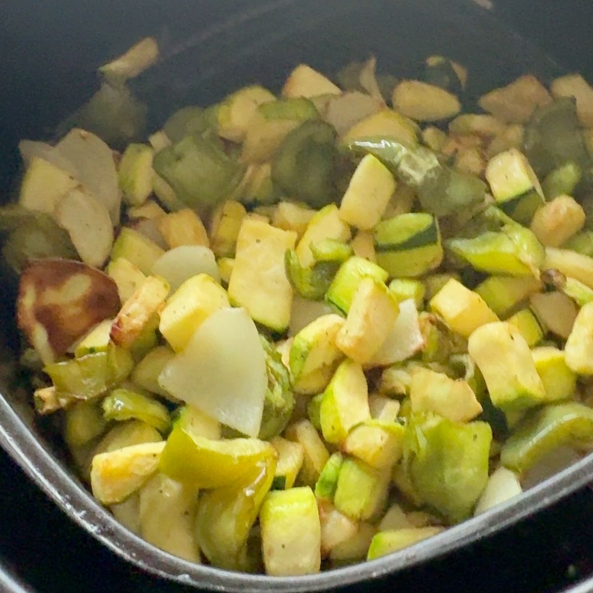 A bowl of perfectly air fried zucchini, peppers, and onions, lightly seasoned and served as a healthy side dish.