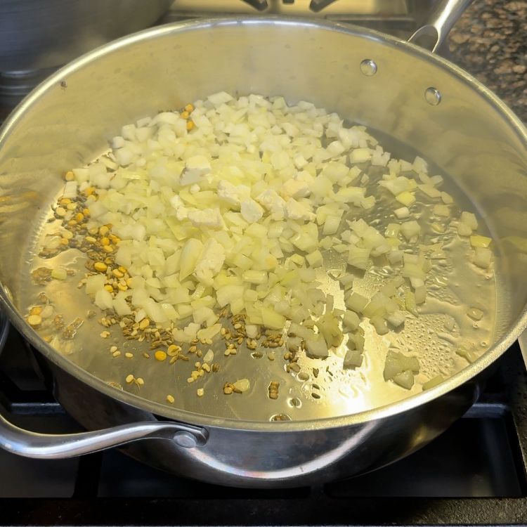 Cooking tempering spices like cumin, mustard seeds, and onions in oil, an essential step for Cauliflower Vepudu Fry.