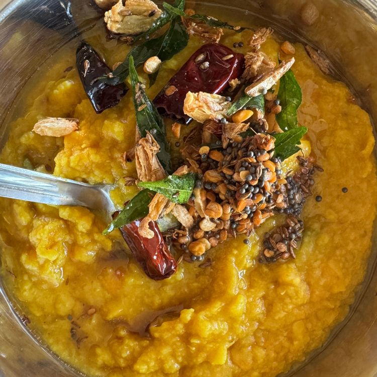 tempering spices on top of cooked dal in a bowl