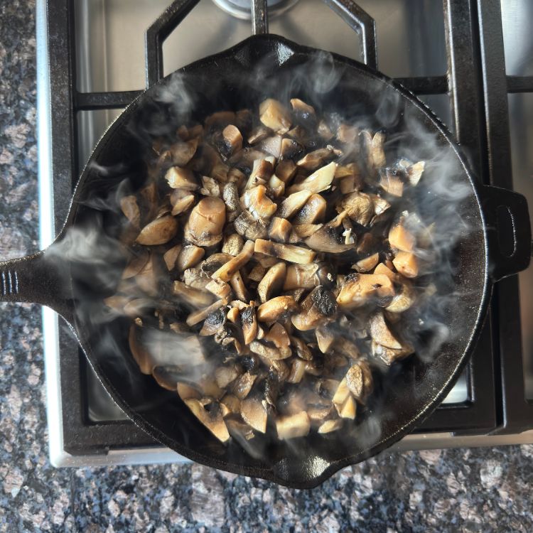 Button mushrooms being sautéed in a hot pan for Indian style mushroom fry recipe