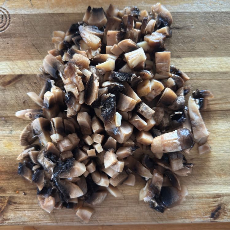 Fresh button mushrooms sliced uniformly on a wooden cutting board for Indian style mushroom fry