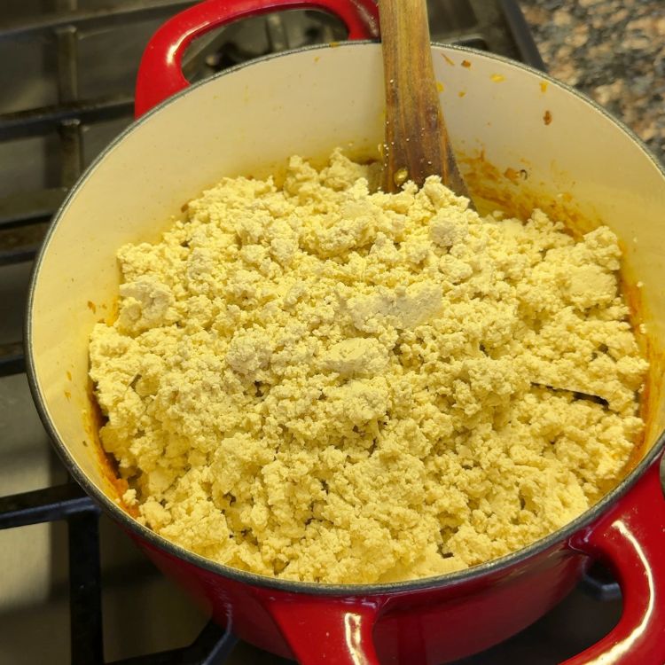 Combining crumbled tofu with masala and cooking until well-incorporated and aromatic