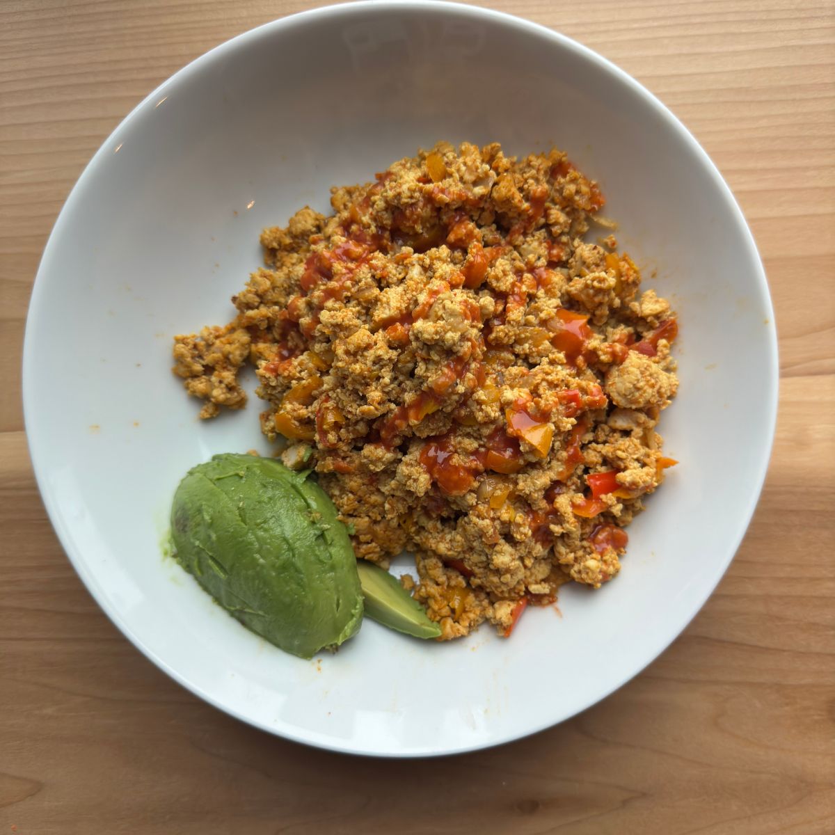 Finished Tofu Burji garnished with avocado and served hot, showing perfect scrambled texture