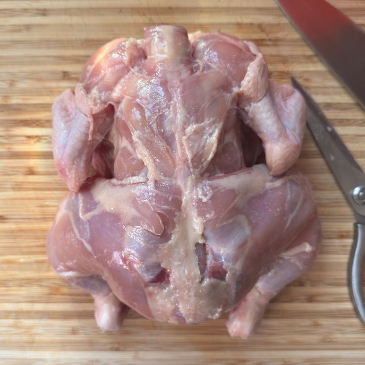 whole chicken with skin removed on the cutting board