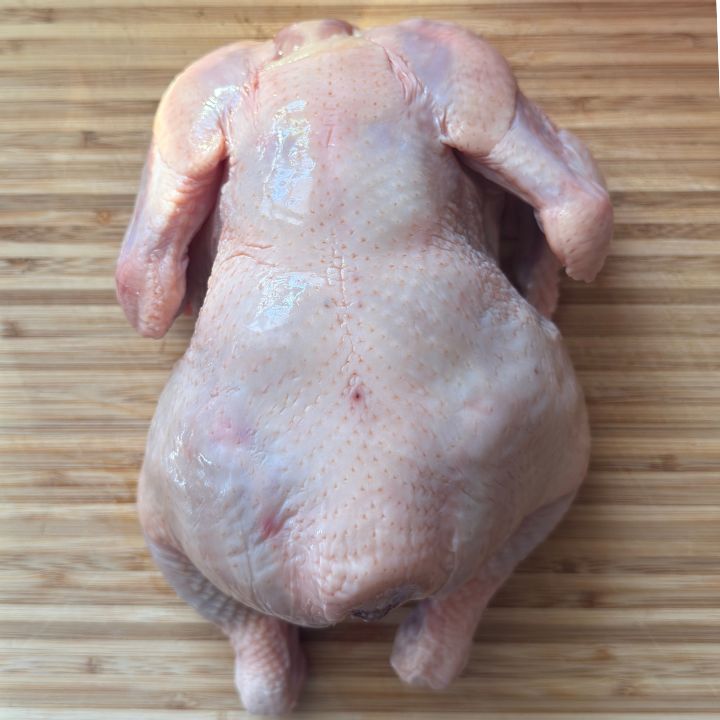 whole chicken with skin on the cutting board