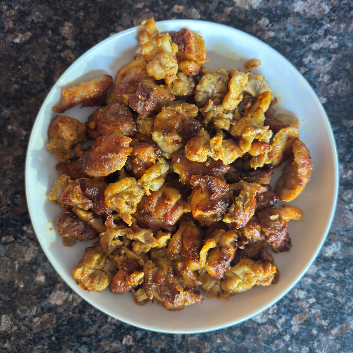 Perfectly baked Indian-style chicken thighs with golden-brown exterior in a serving bowl, ready to eat