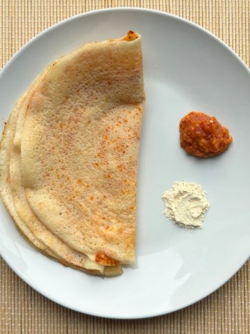 Crispy rice crepe on plate with side of chutney and powder