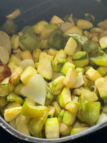 A bowl of perfectly air fried zucchini, peppers, and onions, lightly seasoned and served as a healthy side dish.