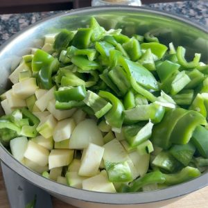 Freshly chopped zucchini, green peppers, and onions in a mixing bowl, ready for seasoning.