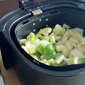 Zucchini, peppers, and onions spread in an air fryer basket, ready to be cooked to crispy perfection.