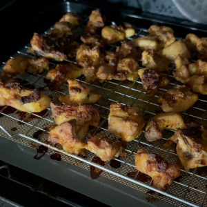 Indian-spiced chicken thighs baking in oven with visible golden-brown crust forming