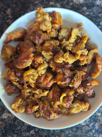 Perfectly baked Indian-style chicken thighs with golden-brown exterior in a serving bowl, ready to eat