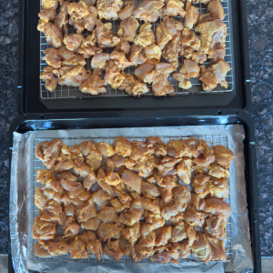 Marinated Indian-style chicken thighs arranged on a wire rack over a baking sheet ready for the oven